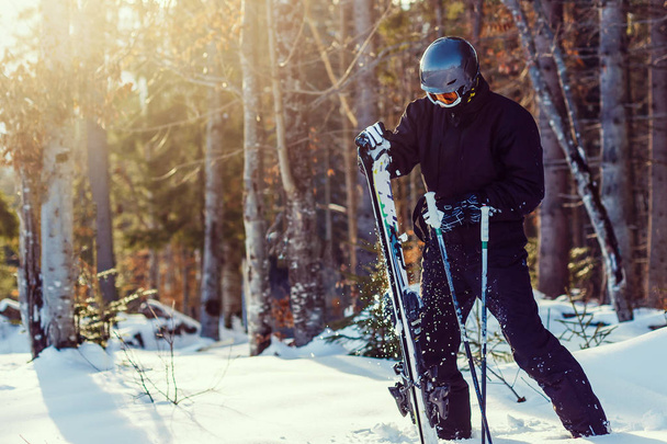 Homem feliz em terno de esqui preto descansando na neve branca
 - Foto, Imagem