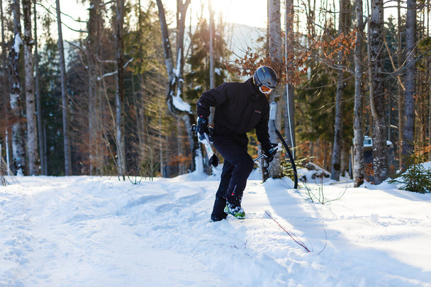 Hombre feliz en traje de esquí negro descansando sobre nieve blanca
 - Foto, Imagen