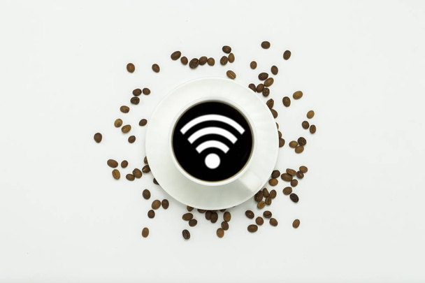 white cup with a saucer and black coffee and a WiFi icon, coffee grains are scattered around on a white background. Flat lay, top view. - Foto, Imagen
