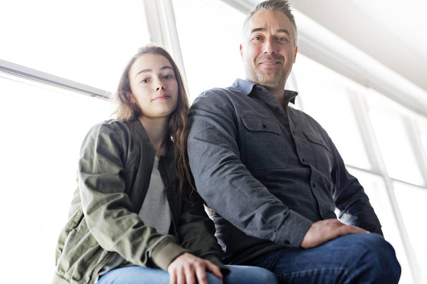 Teenager girl sitting on window with father - Foto, afbeelding