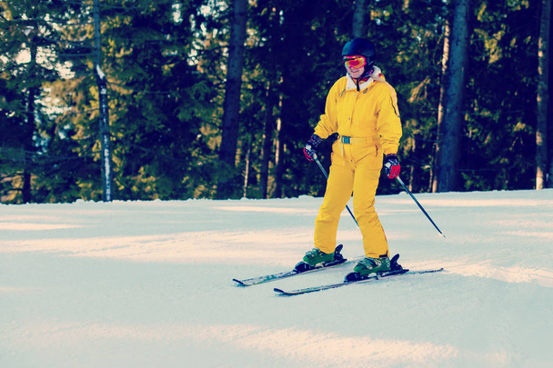 Femme en combinaison d'hiver jaune skis d'équitation dans les montagnes enneigées
  - Photo, image