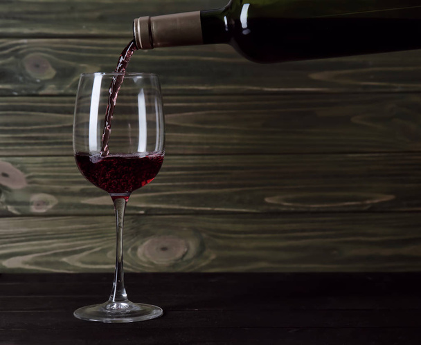 El vertido del vino de la botella en el vaso a la mesa
 - Foto, imagen