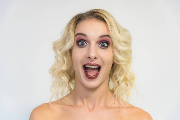 Beauty portrait of a beautiful blonde girl on a white background with perfect makeup. Beauty style model is right in front of the camera and looks happy. - 写真・画像