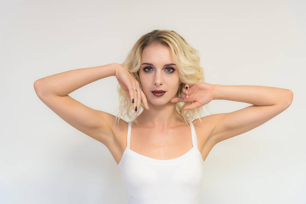 Beauty portrait of a beautiful blonde girl on a white background with perfect makeup. Beauty style model is right in front of the camera and looks happy. - Foto, Imagen