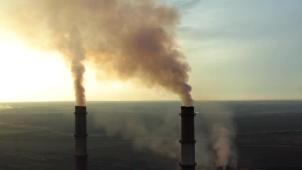 Βιομηχανική ζώνη με ένα μεγάλο κόκκινο και άσπρο σωλήνα παχύς λευκός καπνός χύνεται από το σωλήνα του εργοστασίου σε αντίθεση με τον ήλιο. Ρύπανση του περιβάλλοντος: ένας σωλήνας με καπνό. Αεροφωτογραφία - Πλάνα, βίντεο