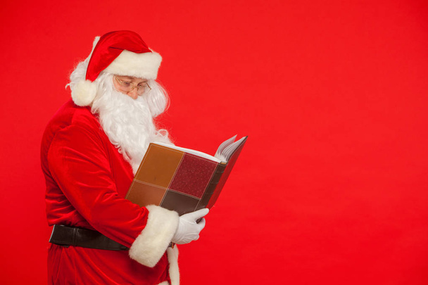 Santa Claus reads old book, on a red background. Christmas - Foto, Imagem