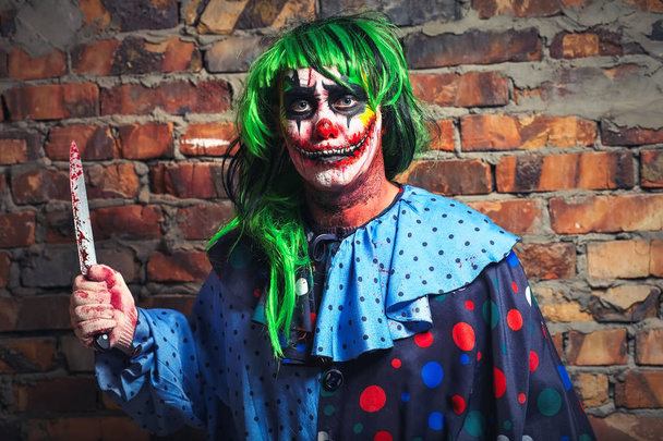 Šílený klaun s nožem na pozadí cihlovou zeď. Koncept Halloween - Fotografie, Obrázek