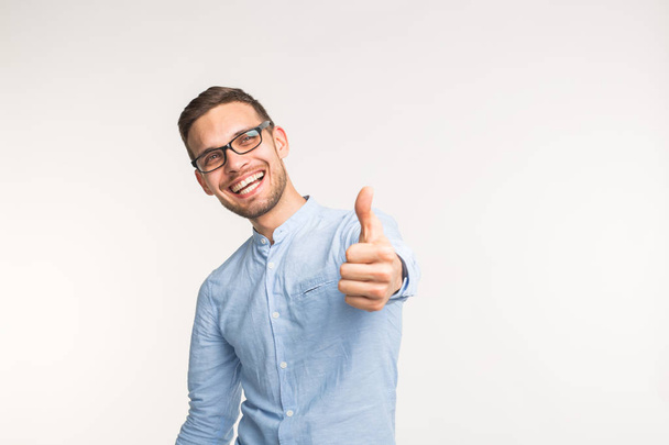 Gesture of approval and correctness concept - Happy handsome man showing thumb up on white background - Photo, Image