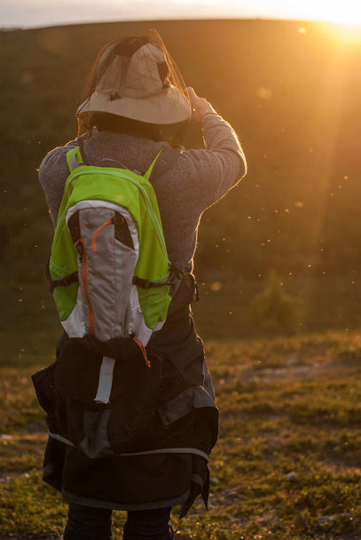 Touriste dans le casque de moustiques dans les rayons du soleil
 - Photo, image