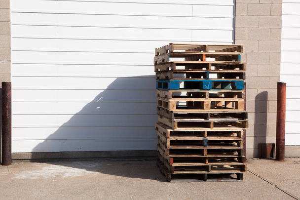 建物のガレージのドアに積み込まれた木製の配送パレット - 写真・画像