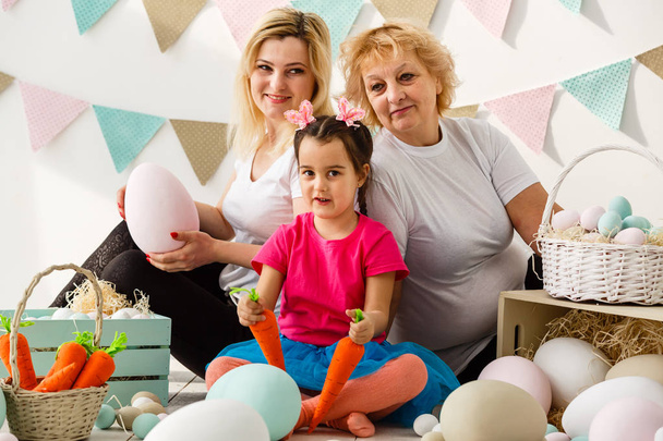Niña feliz con madre y abuela jugando con huevos de Pascua
 - Foto, imagen