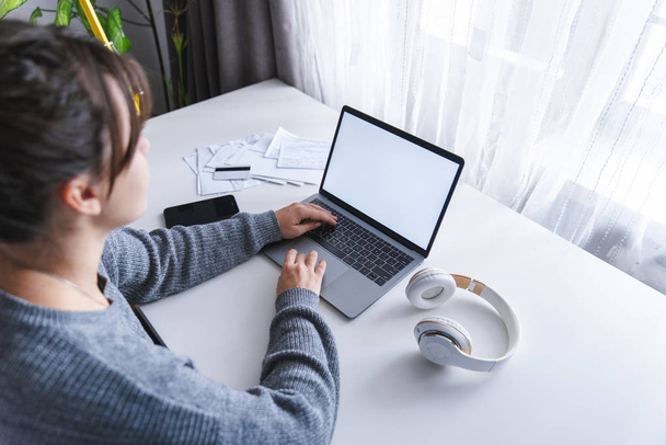 femme assise à la maison travaillant sur un ordinateur portable. écran blanc. espace de copie
 - Photo, image