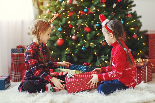 boldog gyerekek lányok a karácsonyi ajándékokat a jó reggelt karácsonyfa közelében - Fotó, kép