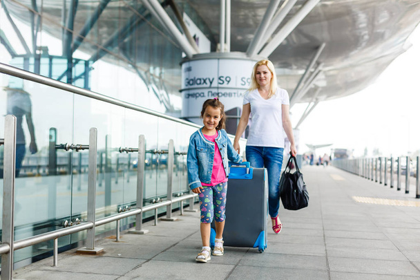 Young mother and daughter with luggage in airport - Zdjęcie, obraz