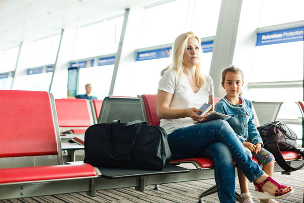 Young mother and daughter waiting for departure at airport waiting room - Photo, Image