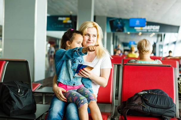 Jonge moeder en dochter wachten op vertrek op vliegveld wachtkamer - Foto, afbeelding