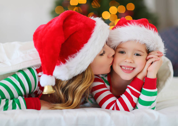 щаслива родина мати і дочка в піжамі відкривають подарунки на Різдвяний ранок біля різдвяної ялинки
 - Фото, зображення