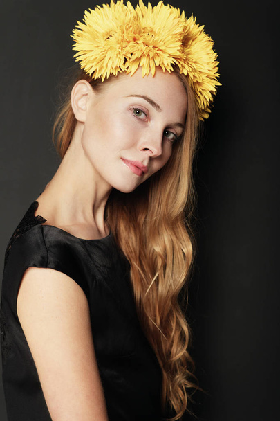 Mujer joven con corona de flores amarillas sobre fondo negro. Concepto de belleza natural
. - Foto, imagen