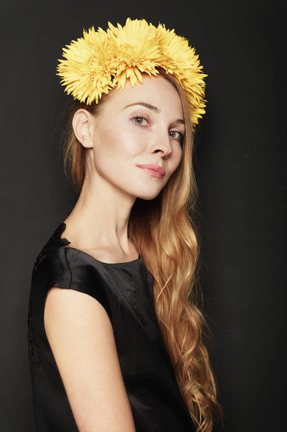 Mujer joven con corona de flores amarillas sobre fondo negro. Concepto de belleza natural
. - Foto, Imagen