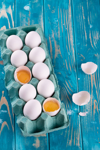 Huevos frescos en una sartén azul. Huevos frescos en una mesa azul con especias. Cubiertos de madera
. - Foto, Imagen