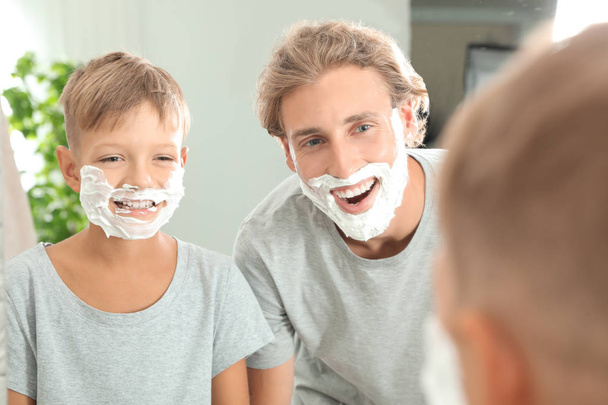 Father and son with shaving foam on faces in bathroom - Фото, зображення