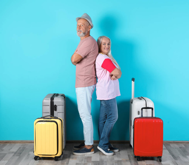Senior couple with suitcases near color wall. Vacation travel - 写真・画像