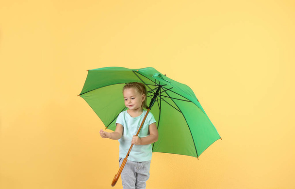 Little girl with green umbrella on color background - Foto, Imagem