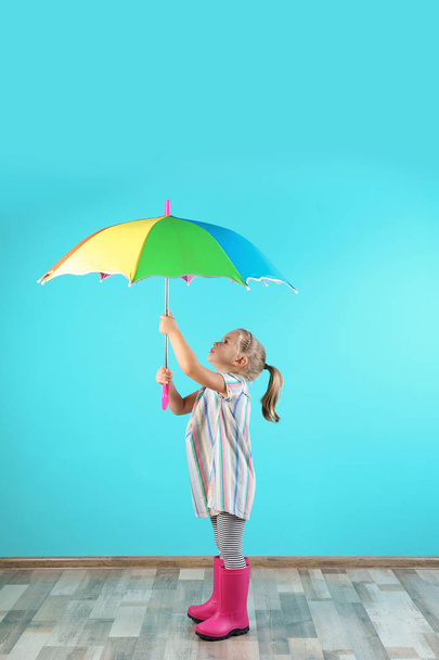 Little girl with rainbow umbrella near color wall - Фото, зображення