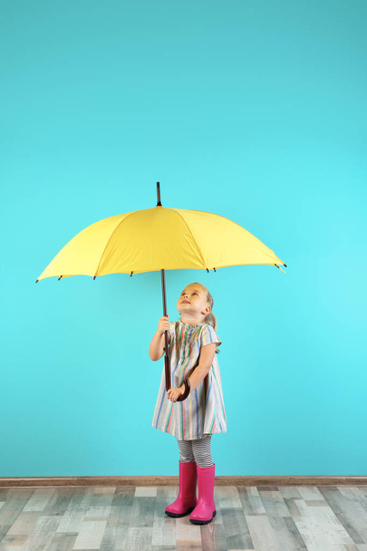 Little girl with yellow umbrella near color wall - Foto, Imagen