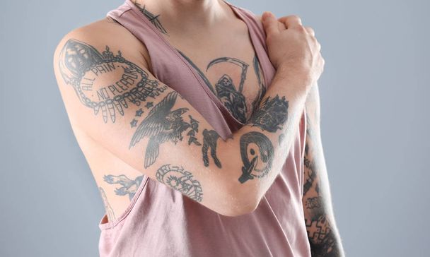 Young man with stylish tattoos on grey background - Photo, Image