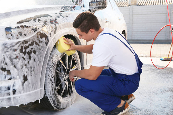 Worker cleaning automobile with sponge at car wash - Foto, afbeelding