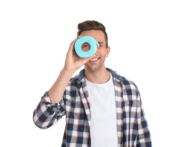 Young man looking through toilet paper roll on white background - Photo, image
