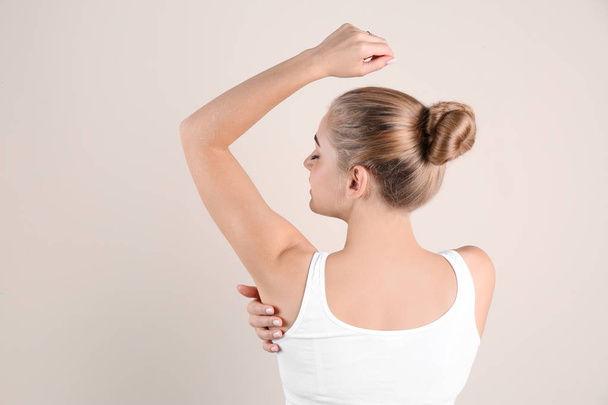 Young woman showing armpit on color background. Using deodorant - Fotoğraf, Görsel