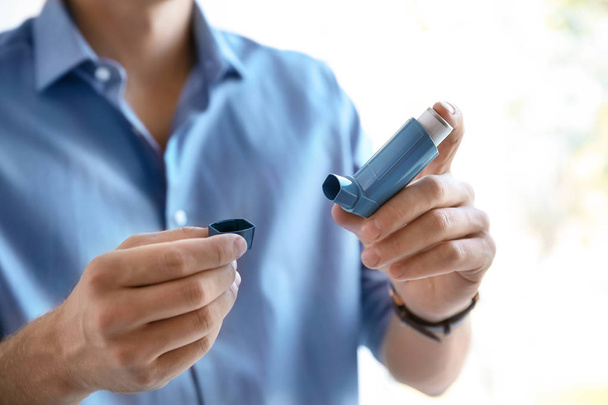 Young man with asthma inhaler indoors, closeup - Photo, image