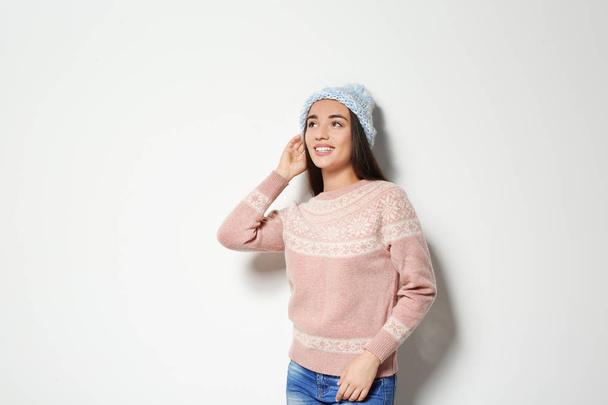 Young woman in warm sweater and knitted hat on white background. Celebrating Christmas - Photo, Image
