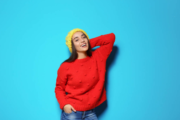 Young woman in warm sweater and hat on color background. Celebrating Christmas - Фото, зображення
