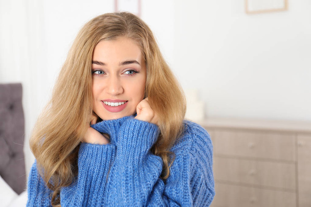 Hermosa mujer joven sonriente en suéter cálido acogedor en casa. Espacio para texto
 - Foto, Imagen