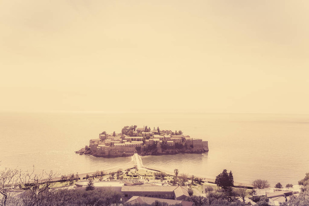 Retro sepia vintage image of the historical Sveti Stefan old town, landmark on the coast of Montenegro - Photo, Image
