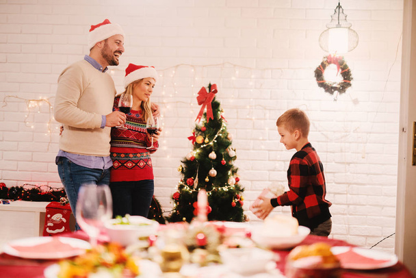 Szczęśliwa rodzina obchodzi Boże Narodzenie w domu rodziców picia wina w pobliżu choinki  - Zdjęcie, obraz