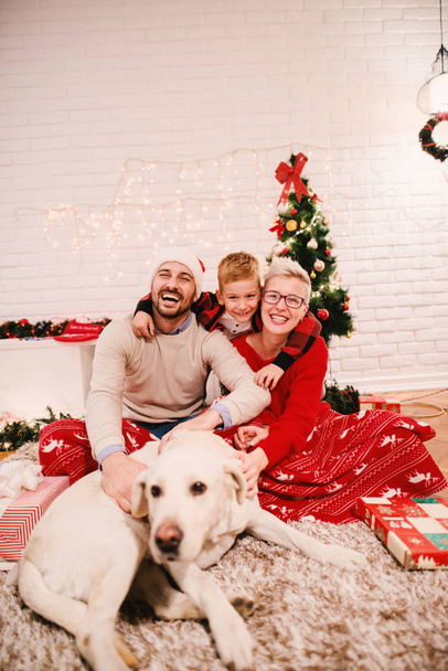giovane famiglia felice che celebra il Natale seduto sul pavimento a casa con adorabile cane Labrador Retriever
 - Foto, immagini
