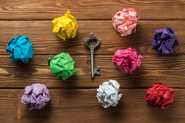 Set of multiple colorful crampled paper ball and key among them, placed on wooden table as means of searching of new ideas. - Fotoğraf, Görsel