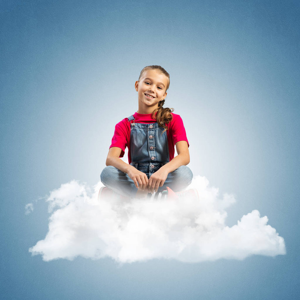 Cute kid girl sitting on cloud against blue color background - Photo, image