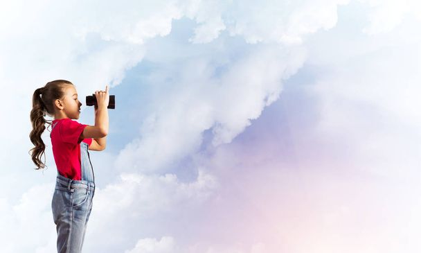 Little cute girl in overalls against sky background dreaming about future - Photo, image
