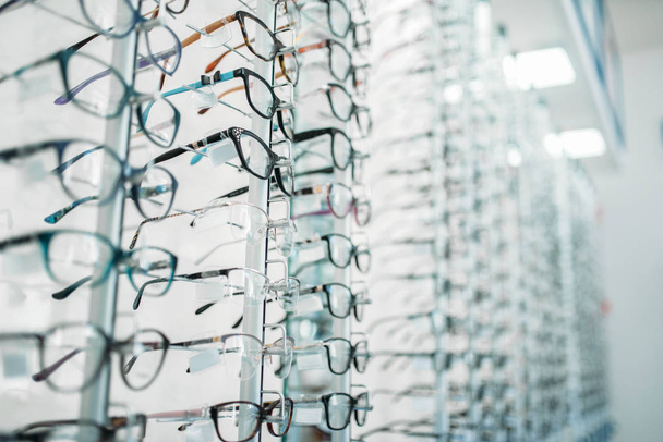 Szemüveget és napszemüveget kirakat optikai üzletben, senki sem. Szemvédelem látás, optikai kiegészítő polcokon - Fotó, kép
