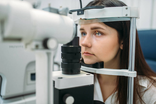 Nuori naispotilas näkökokeessa optikkokaapissa, näön diagnostiikka, ammattimainen silmälasien valinta. Asiantuntijan kuuleminen, silmätaudit
 - Valokuva, kuva