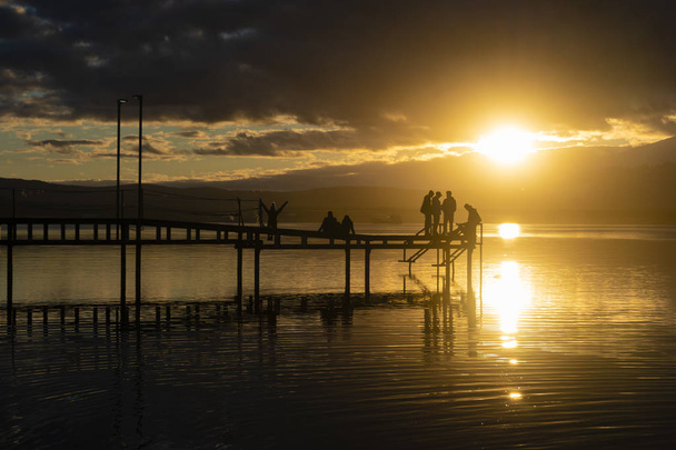 People relaxing at a pier during sunset - Photo, image