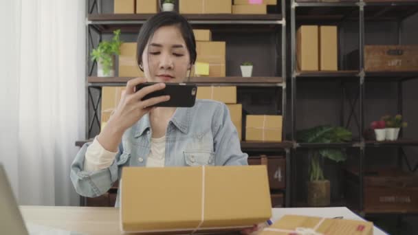 Gyönyörű ázsiai intelligens fiatal vállalkozó nő cégtulajdonos a KKV-k ellenőrzése termék tőzsdei keresés qr-kód otthoni munkavégzés. Kisvállalkozás tulajdonosa, otthoni iroda koncepció:. - Felvétel, videó