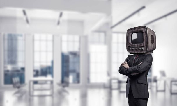 Cropped image of businessman in suit with old TV instead of head keeping arms crossed while standing inside office building. - Foto, immagini