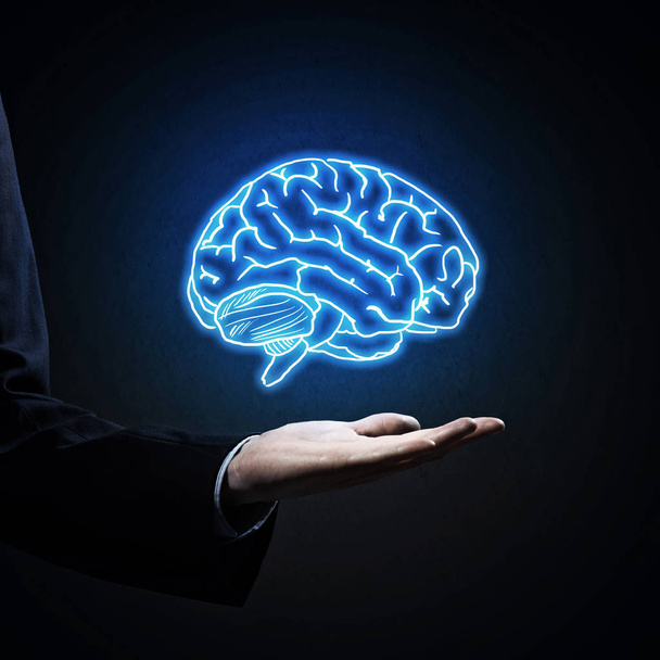 Close up of businessman hand holding brain in palm - Foto, afbeelding