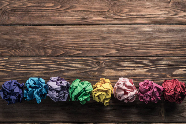 Conjunto de bolas de papel trituradas de colores múltiples colocadas en línea en la mesa de madera como medio de búsqueda de nuevas ideas
. - Foto, imagen